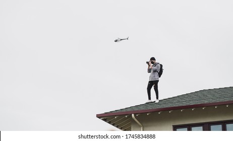 Protester on the roof of The Grove in West Hollywood, California taking photos during the George Floyd protests, with a helicopter flying behind him.