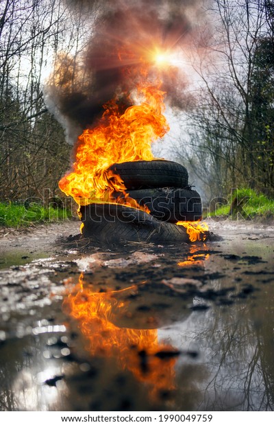 Protesters burn car tires on a\
country road. Fire, black smoke, strong odor and release of toxic\
gases