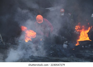 Protesters in helmets burn tires on the Maidan barricades to stop the riot police during Mass anti-government protests Euromaidan on January 2014 in Kyiv, Ukraine  - Shutterstock ID 2230547279