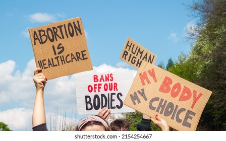 Protesters holding signs Abortion Is Healthcare, My Body My Choice, Bans Off Our Bodies, Human rights. People with placards supporting abortion rights at protest rally demonstration.