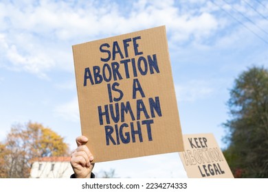 Protesters holding signs with slogans Safe abortion is a human right and Keep abortion legal. People with placards supporting abortion at protest rally demonstration.