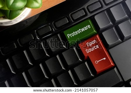 Protestware and Open Source key on a pc keyboard. Protestware is when a programmer insert malicious content into an open source code in order to make a political statement.