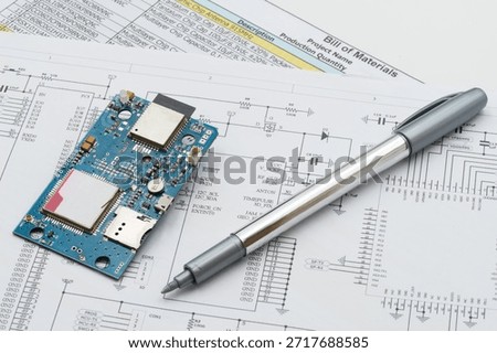 Prototype circuit board placed on schematic and BOM documents, illustrating electronics design review, component verification, and engineering workflow before production.