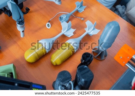 Prototype model of rocket bomb tip printed on 3D printer. Small colored models of tail fins, tail cone printed on 3D printer from molten plastic on table. New modern innovation printing technology