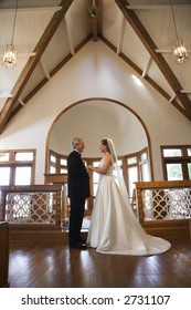 Protrait Of Bride And Groom Holding Hands At The Alter Of A Church.