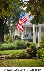 A Proud American Flag Is Lit By The Sun In A Small Town Neighborhood.