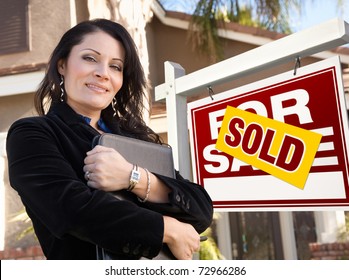 Proud, Attractive Hispanic Female Agent In Front Of Sold For Sale Real Estate Sign And House.