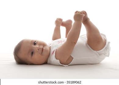 Proud Baby Girl Holding Feet Lying On Her Back On The Floor