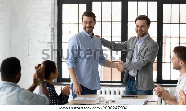 Proud boss encouraging and thanking happy employee\
for good job, shaking hand. Excited worker getting promotion,\
recognition, respect and applause of colleagues. Leader introducing\
new team member