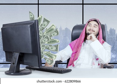 Proud Businessman Looking At Money Flying Out Of Monitor With Winter Background On The Window 