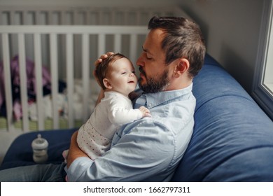 Proud Caucasian Father Talking To Newborn Baby Girl. Parent Holding Rocking Child Daughter In Hands. Authentic Lifestyle Happy Parenting Fatherhood Moment. Single Dad Family Home Life.