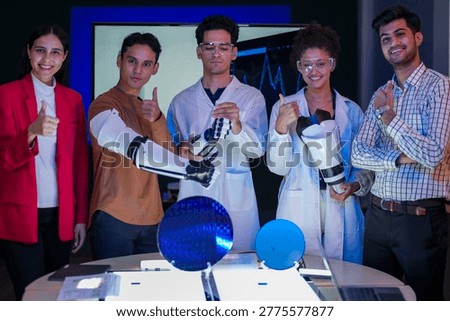 Proud diverse STEM workforce displaying advanced robotic arm and silicon wafer in R D lab. Leading the future of AI technology and cybernetic hardware innovation.Diverse team of scientists and engineers collaborating on robotics and semiconductor research in a high tech laboratory at night. Innovation and hardware development concept.