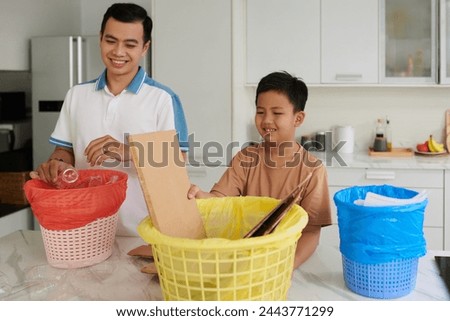 Proud father teaching son to sort and categorize trash