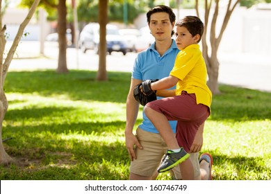 Proud Father Watching His Son Practice Baseball At A Park