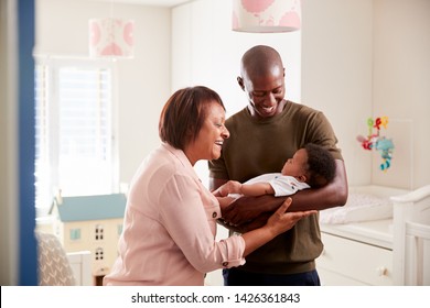 Proud Grandmother With Adult Son Cuddling Baby Grandson In Nursery At Home - Powered by Shutterstock