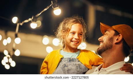 Proud Handsome Father Helping His Little Beautiful Daughter to Change a Lightbulb in Fairy Lights Backyard Installation at Home. Father and Daughter Repair Lights on a Porch.