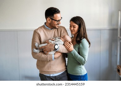 Proud mother and father smiling at their newborn baby daughter, son at home - Powered by Shutterstock