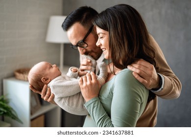 Proud mother and father smiling at their newborn baby daughter, son at home - Powered by Shutterstock