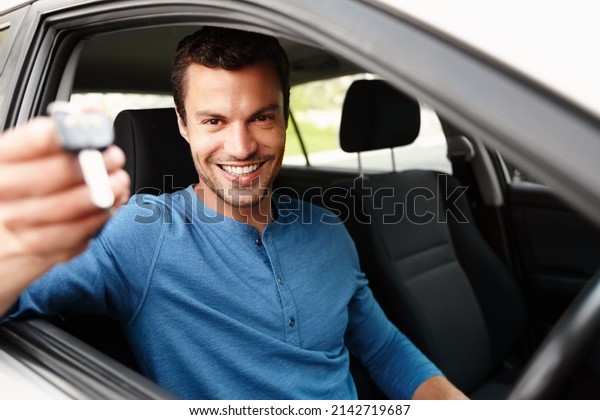 Proud new car owner. Smiling male sitting in his\
car holding up his car\
keys.