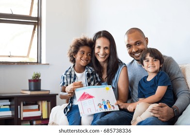Proud parents showing family painting of son sitting on sofa at home. Smiling mother and father with children?. Black boy with his family at home showing a painting of a happy multiethnic family.