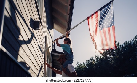 Proud Patriotic Dad Holding His Young Daughter of His Shoulders, Helping Her to Put the United States of America Flag on the Wall of Their House to Celebrate a National Holiday. Sunny Day in USA. - Powered by Shutterstock