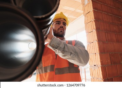 Proud People Working In Construction Site. Portrait Of Happy White Man At Work In New House. Professional Latino Worker Carrying Pipes And Looking Away