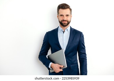 Proud positive successful caucasian bearded businessman in a suit, seo, executive, broker, financial adviser, standing on isolated white background, holding laptop, looking at camera, smiling - Shutterstock ID 2253985939