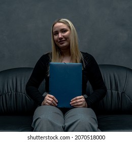 Proud Private School Student Presenting Her Business Idea, She's In An Office, She's Sitting On A Dark Leather Couch While Holding Her Documents In Her Lap.