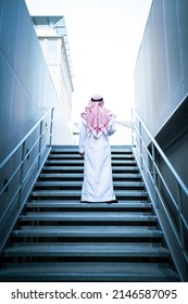 Proud Saudi Arab man approaching the future climbing stairs. Emirati successful muslim man moving forward to new challenges wearing traditional