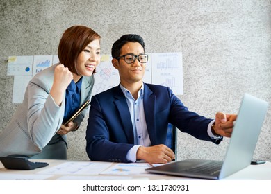 Proud smiling Vietnamese businessman showing colleague his work on laptop screen - Shutterstock ID 1311730931