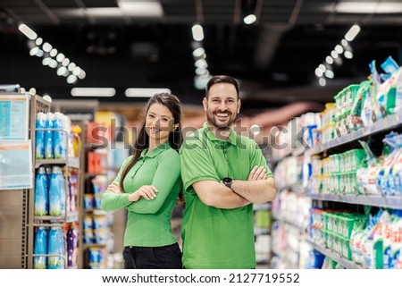 Proud supermarket employees standing and smiling at the camera.