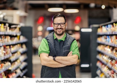 A proud supermarket seller is standing with arms crossed at marketplace and smiling at the camera. - Shutterstock ID 2256142065