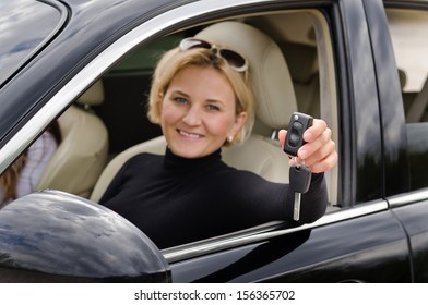 Proud Woman Driver Holding Up Her Car Keys Out Of The Open Window Of The Vehicle To Show That She Has Just Purchased A New Car