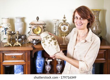 Proud Woman Holding Vase From Her Collection Of Antiques