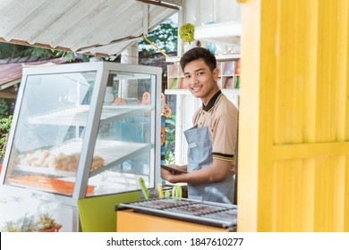 proud young asian man small business owner at his shop made of truck container selling street food - Powered by Shutterstock