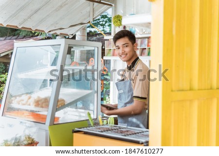 proud young asian man small business owner at his shop made of truck container selling street food
