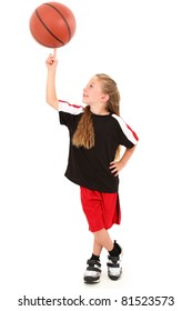 Proud young girl child basketball player in uniform spinning ball on finger over white background.