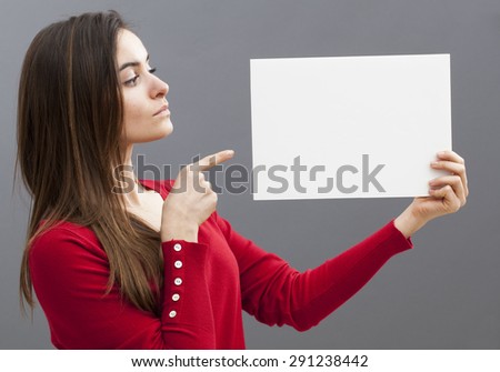 proud young lady pointing at a claim on blank  board that she holds from profile