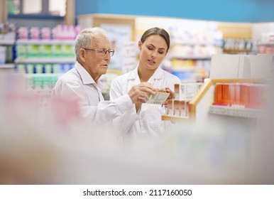Providing Clients With All The Facts. Shot Of A Young Pharmacist Helping An Elderly Customer.
