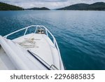 The prow of a fast boat or yacht that is speeding in the ocean heading for an island. The ship is sailing on the sea during the day. High Angle Photo Daylight. Concept for luxury trip and vacation.