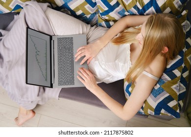 Prudent woman looks at the fluctuations of the exchange rate on the stock exchange while staying at home (view from above)