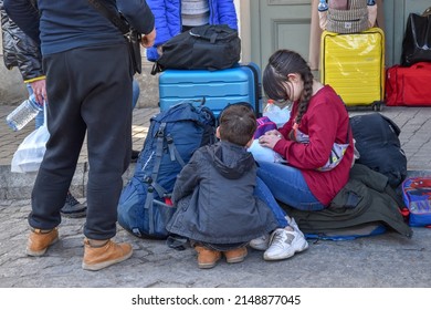 Przemysl, Poland, 03 25 2022 - Children from Ukraine are sitting on their luggage waiting for transportation in Poland. Refugees from Ukraine on the border with Poland.