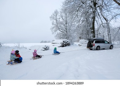 Przywidz, Poland - January 13, 2021: Young Children Go Sledding On A Sleigh Ride With Car Along A Beautiful Snowy Road In The Forest. Przywidz, Kashubia, Poland