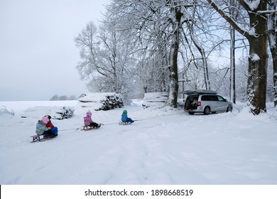 Przywidz, Poland - January 13, 2021: Young Children Go Sledding On A Sleigh Ride With Car Along A Beautiful Snowy Road In The Forest. Przywidz, Kashubia, Poland