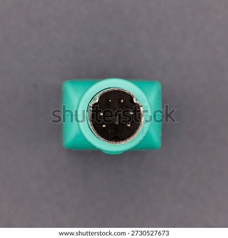 Ps2 connector for a computer mouse with green plastic casing on a gray background