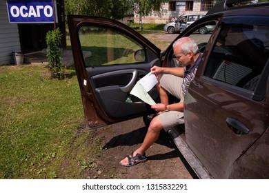 Pskov Region. Russia - July 5, 2018: Point Of Sale Of Green Car Cards And Insurance CTP On The Border With The Republic Of Belarus. Man Examines Insurance Documents.