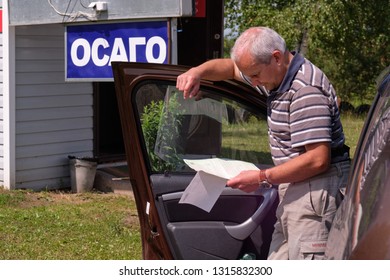 Pskov Region. Russia - July 5, 2018: Point Of Sale Of Green Car Cards And Insurance CTP On The Border With The Republic Of Belarus. Man Examines Insurance Documents.