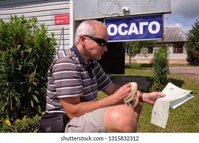 Pskov Region. Russia - July 5, 2018: Point Of Sale Of Green Car Cards And Insurance CTP On The Border With The Republic Of Belarus. Man Examines Insurance Documents.