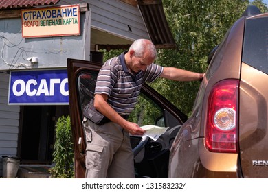 Pskov Region. Russia - July 5, 2018: Point Of Sale Of Green Car Cards And Insurance CTP On The Border With The Republic Of Belarus. Man Examines Insurance Documents.