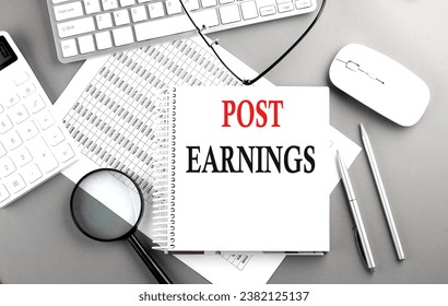 PST EARNINGS text on a notebook with clipboard and calculator on a chart background